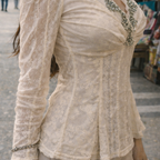 Woman wearing a lace top with decorative elements in an outdoor setting