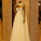 Elegant evening gown on a mannequin against a beige wall.