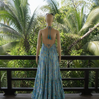 Mannequin wearing a blue floral dress on a wooden deck with tropical plants in the background