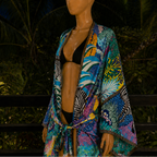 Mannequin wearing a colorful kimono with a tropical pattern against a dark background.