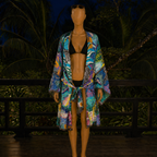Mannequin wearing a colorful robe over a black bikini set with a tropical background.