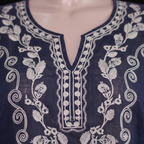 Close-up of a navy blue embroidered tunic top displayed on a mannequin torso, featuring intricate white floral and scroll embroidery around a split neckline.
