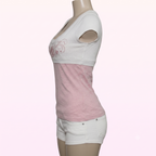 A women's short-sleeve crop top in a colorblock design of white and light pink, shown on a mannequin torso. The top features a white upper section with a pink butterfly graphic on the left chest, a solid pink middle section, and a white lower hem with cutout details in the sleeves.