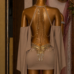 Mannequin wearing a beige dress with intricate gold detailing in a decorative setting.